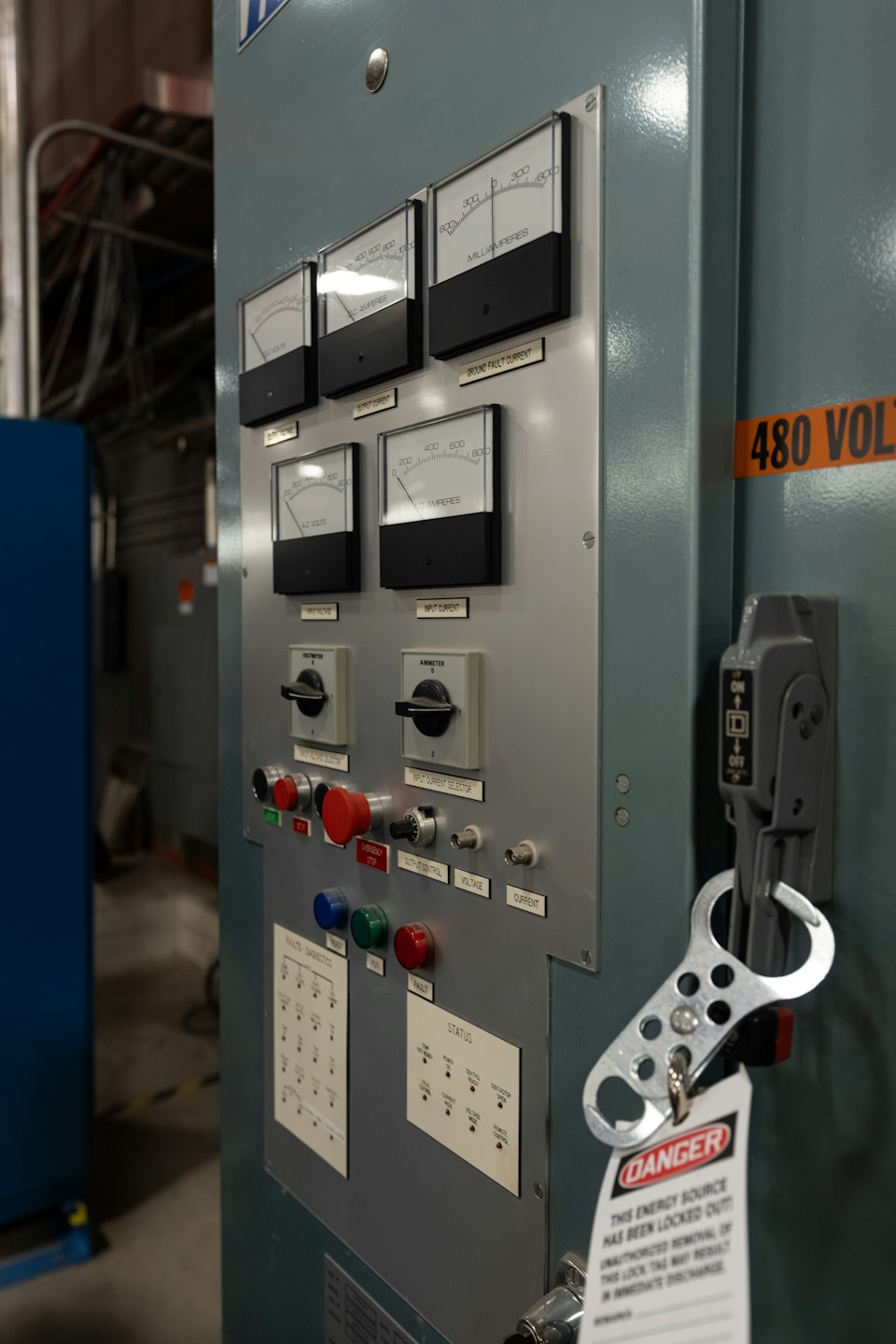 Industrial electrical panel with gauges, switches, and warning tape.