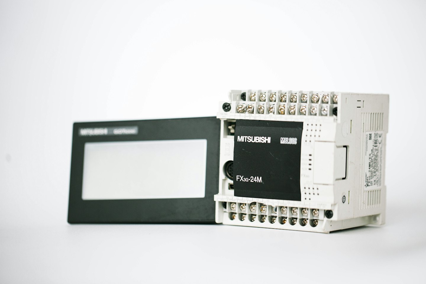 Industrial PLC and HMI screen arranged on a white surface.